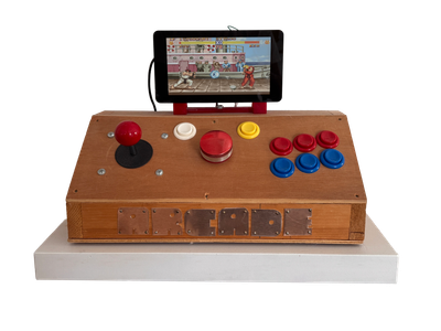 A wooden desktop arcade console sits on a shelf. It has a joystick, spinner and buttons. A small screen atop displays Street Fighter.