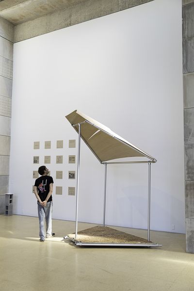 A man looks up at a built happenspace module in a brightly-lit gallery space.
